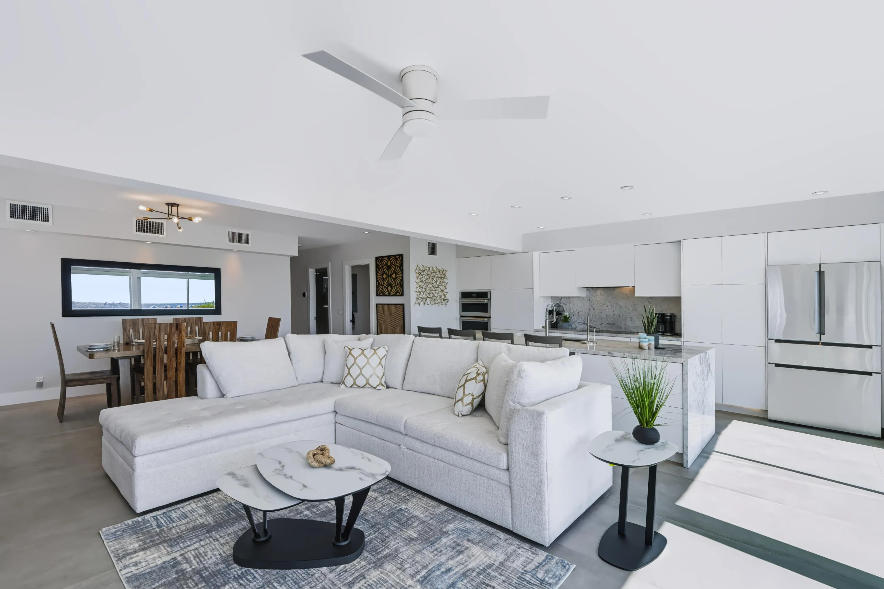 Open-concept living area featuring a modern kitchen with flat-panel cabinetry, stainless steel appliances, and a waterfall island
