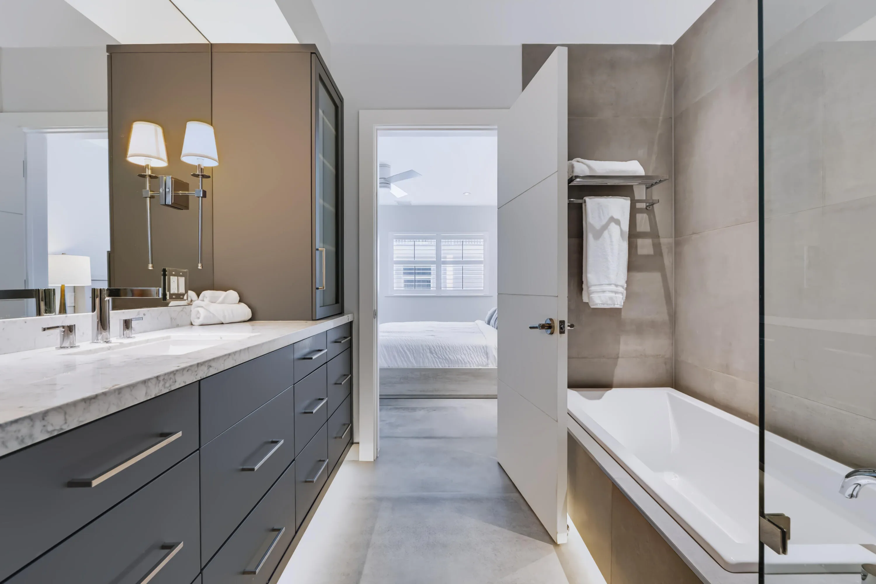 Dual vanity with an integrated basin, contemporary wall sconces, a built-in tub, and a glass shower enclosure