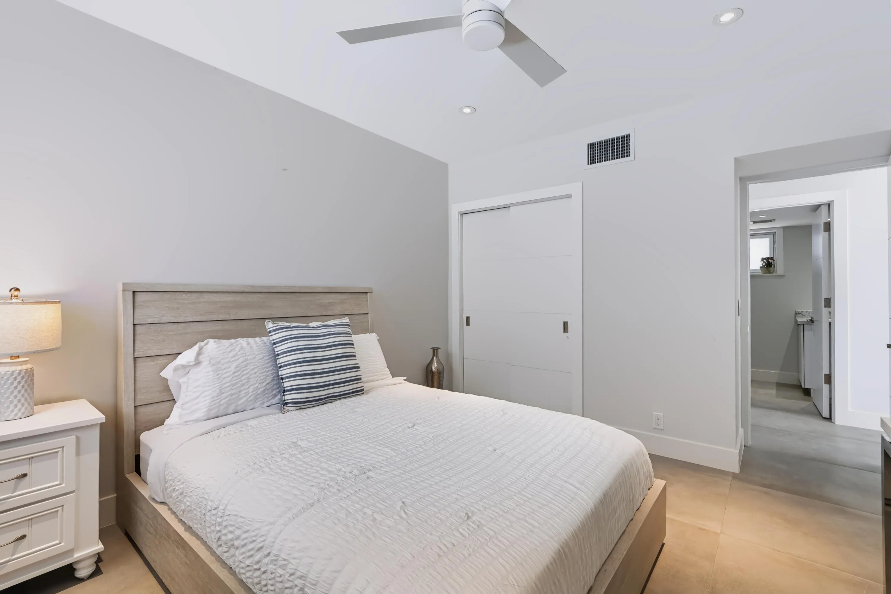 Recessed lighting, ceiling fan, sliding closet doors, wood-finish bed frame, and tile flooring