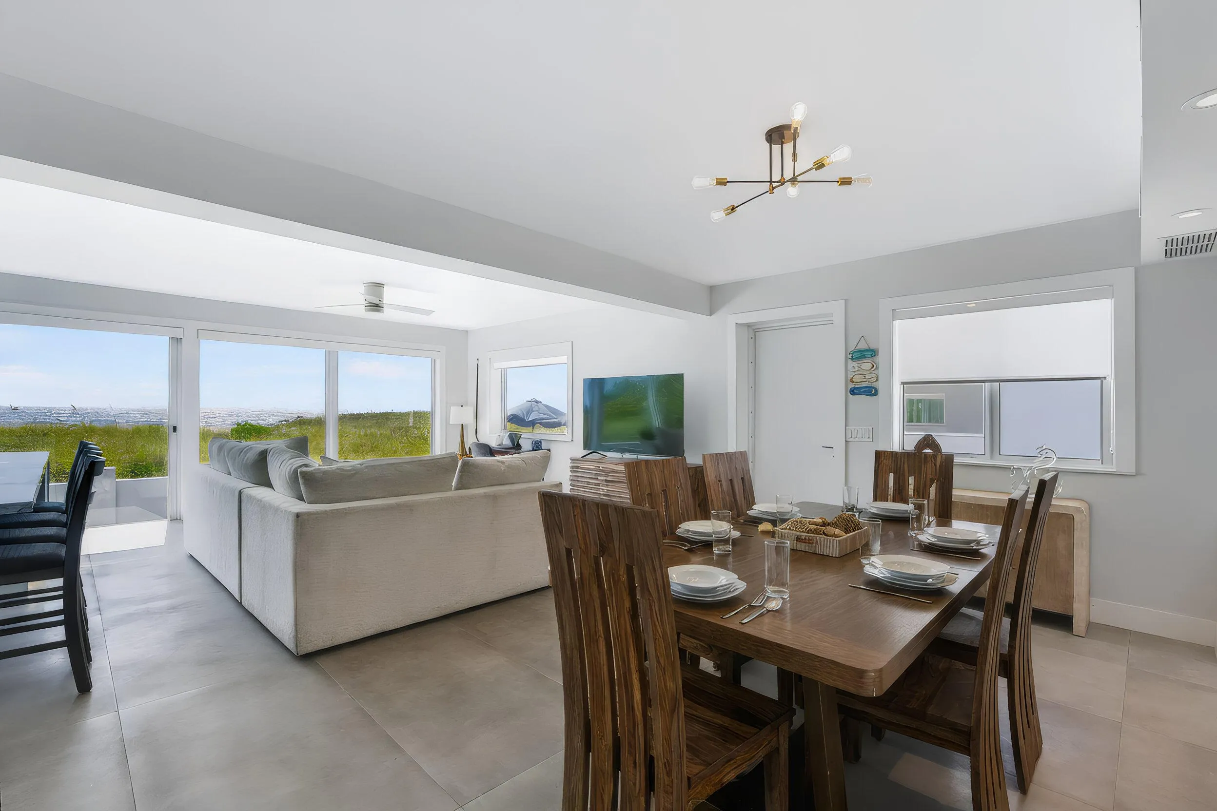 Open-concept living space with large format tile flooring and a contemporary linear chandelier