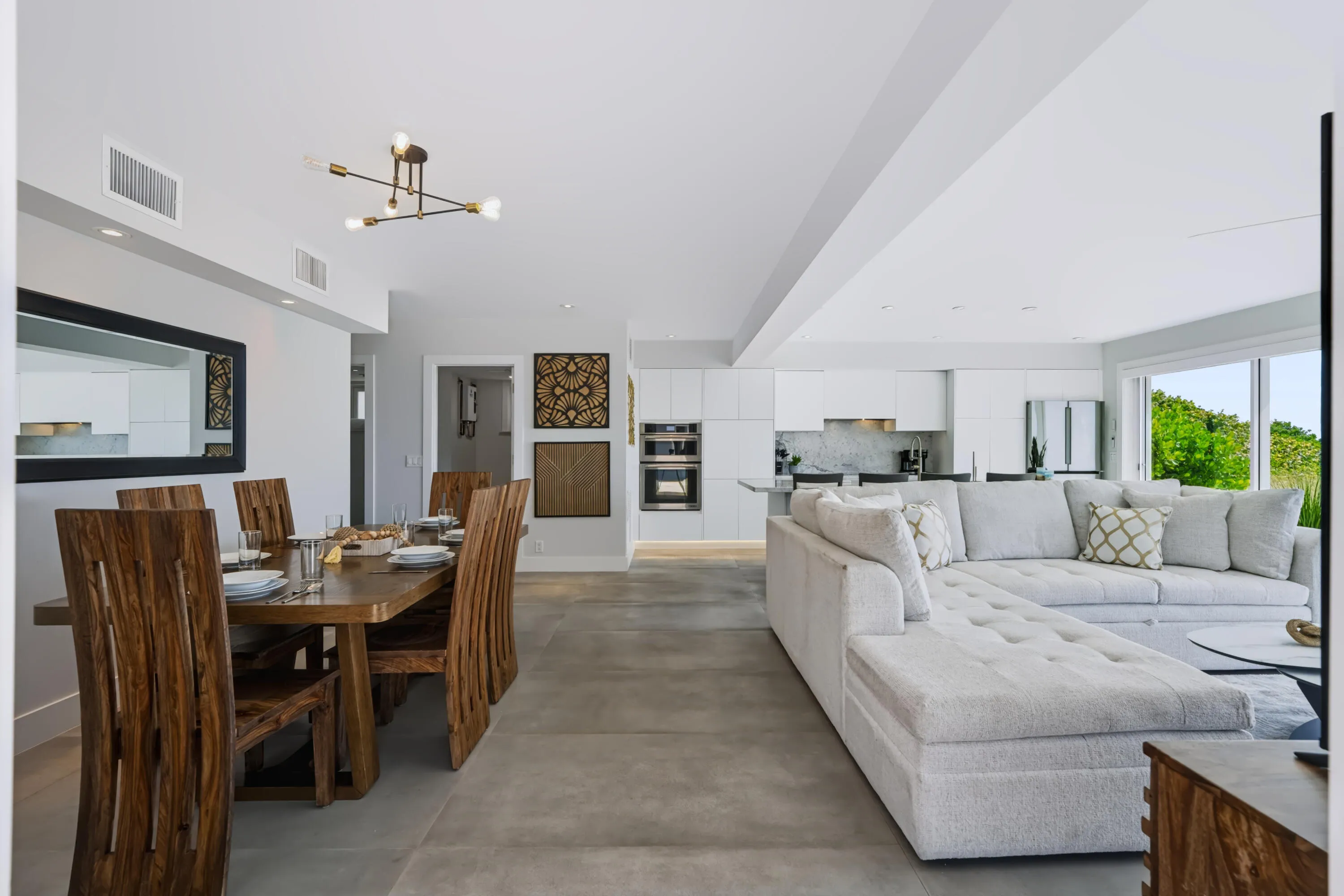 Open-concept living space featuring high ceilings, recessed lighting, expansive glass sliding doors, and light-toned flooring