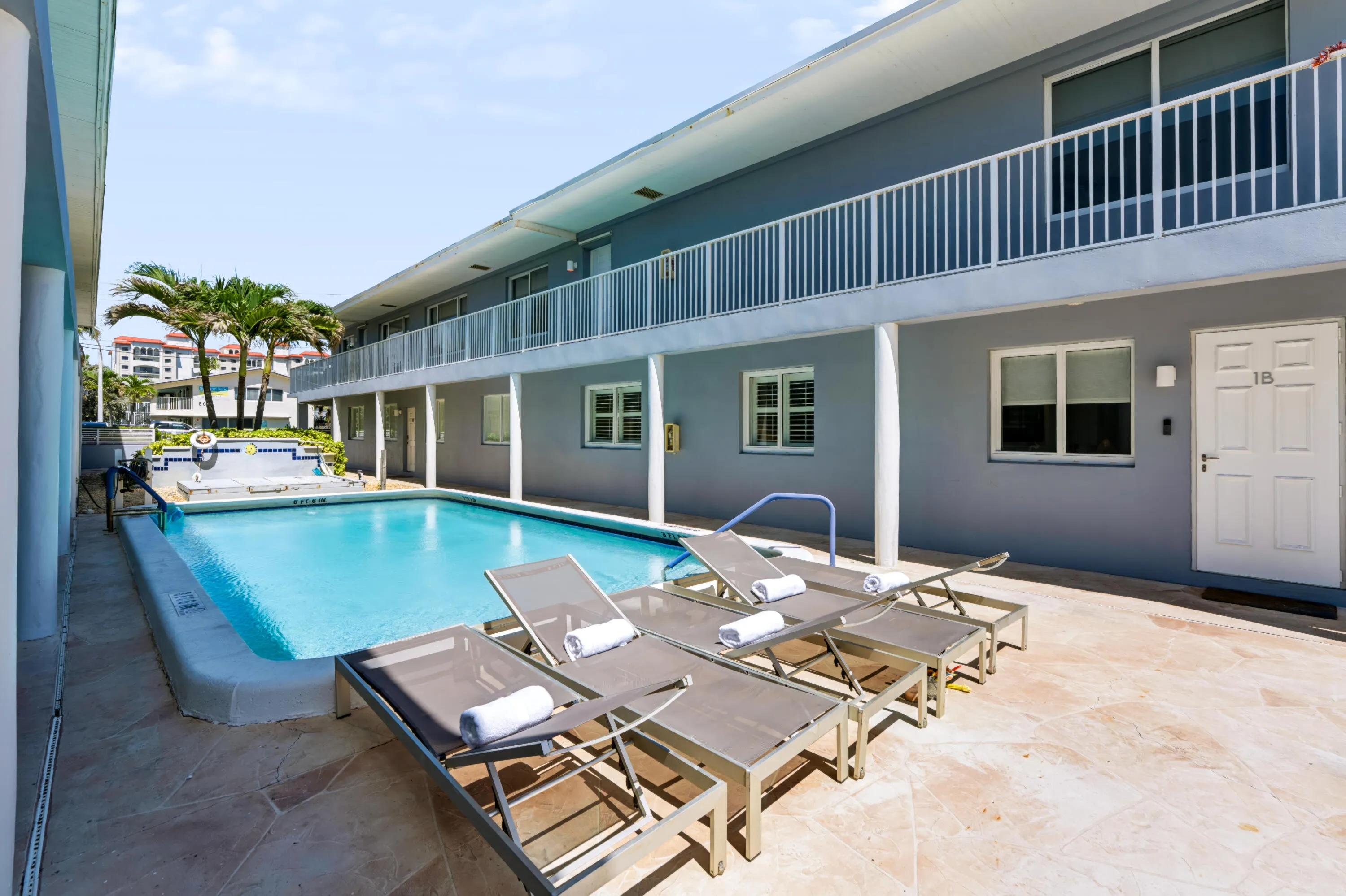 Outdoor swimming pool with tiled surround, adjacent to a patio with stone-finish pavers