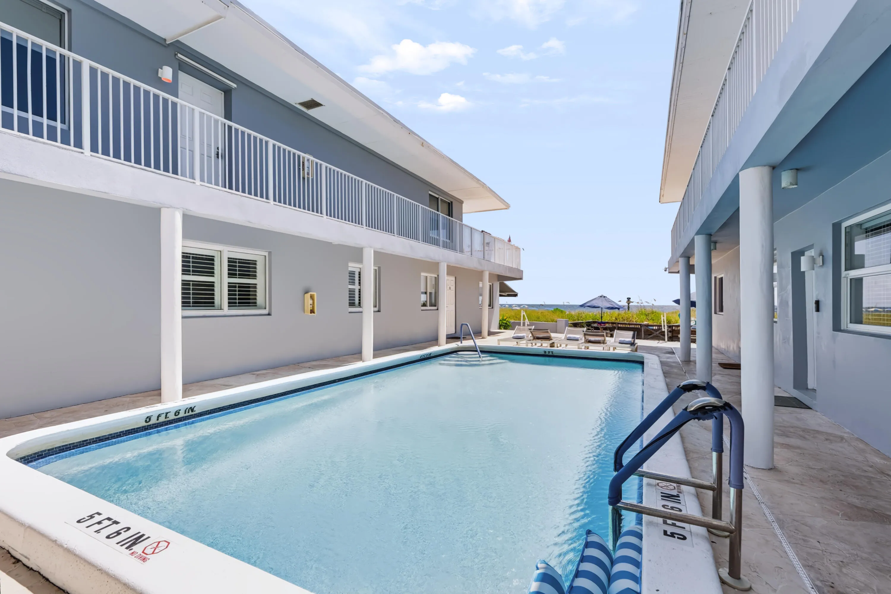 In-ground swimming pool with direct beach access, surrounded by a concrete patio