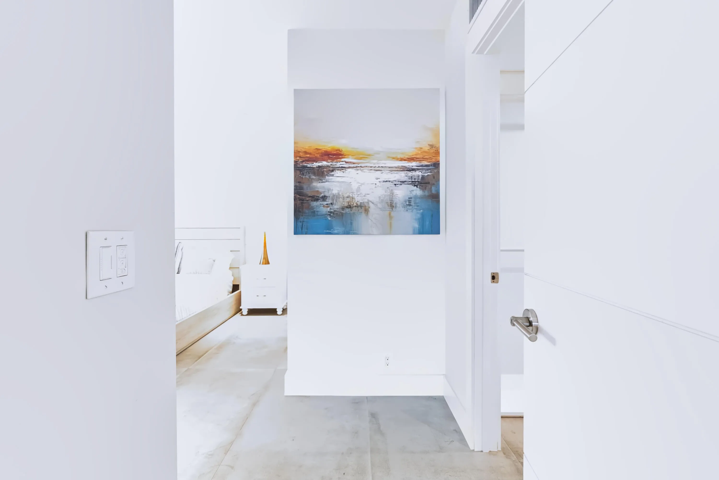 White interior walls, modern light switches, white door with brushed nickel hardware, light-toned flooring, recessed lighting