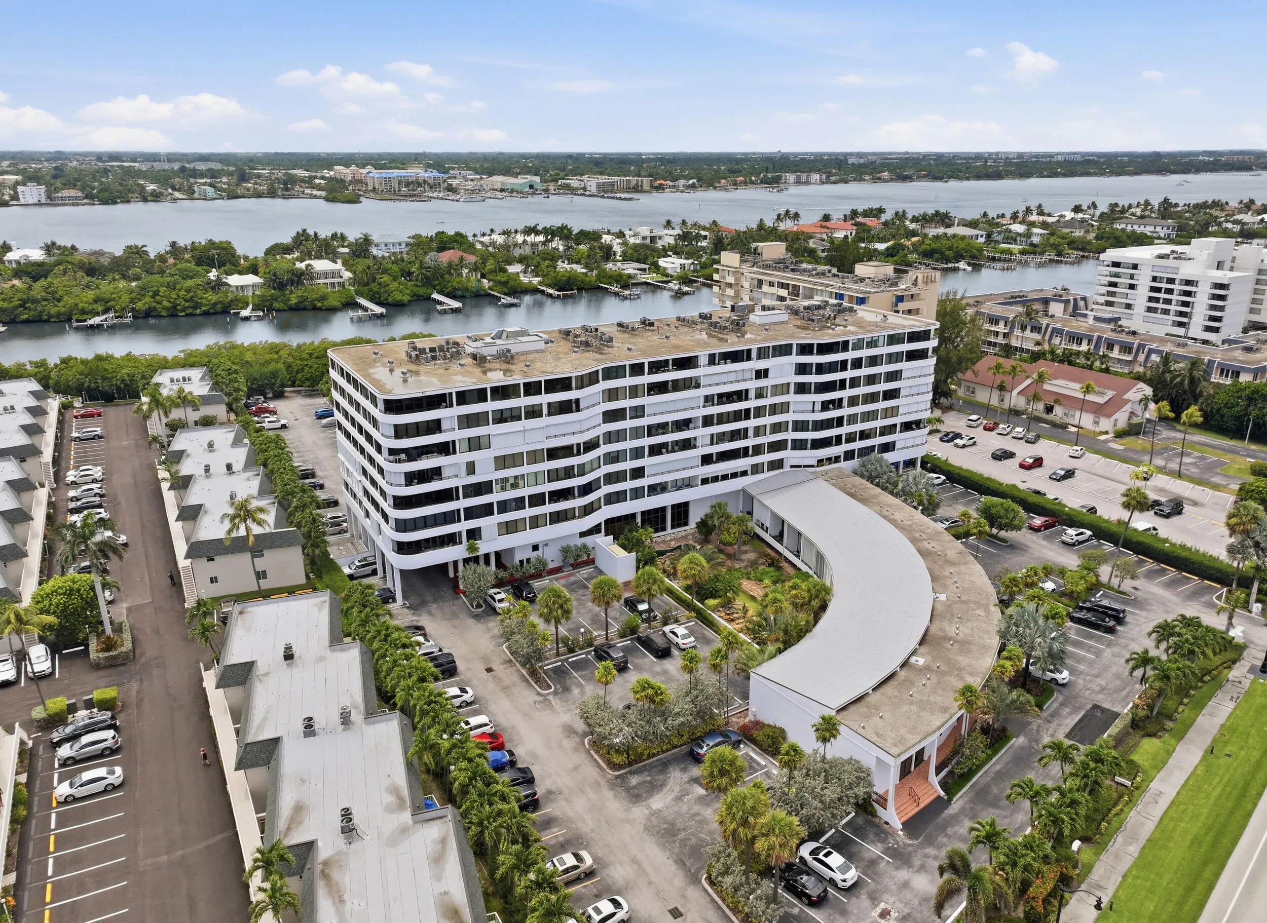 Modern multi-story building featuring multiple balconies, a curved architectural element, and integrated landscaping