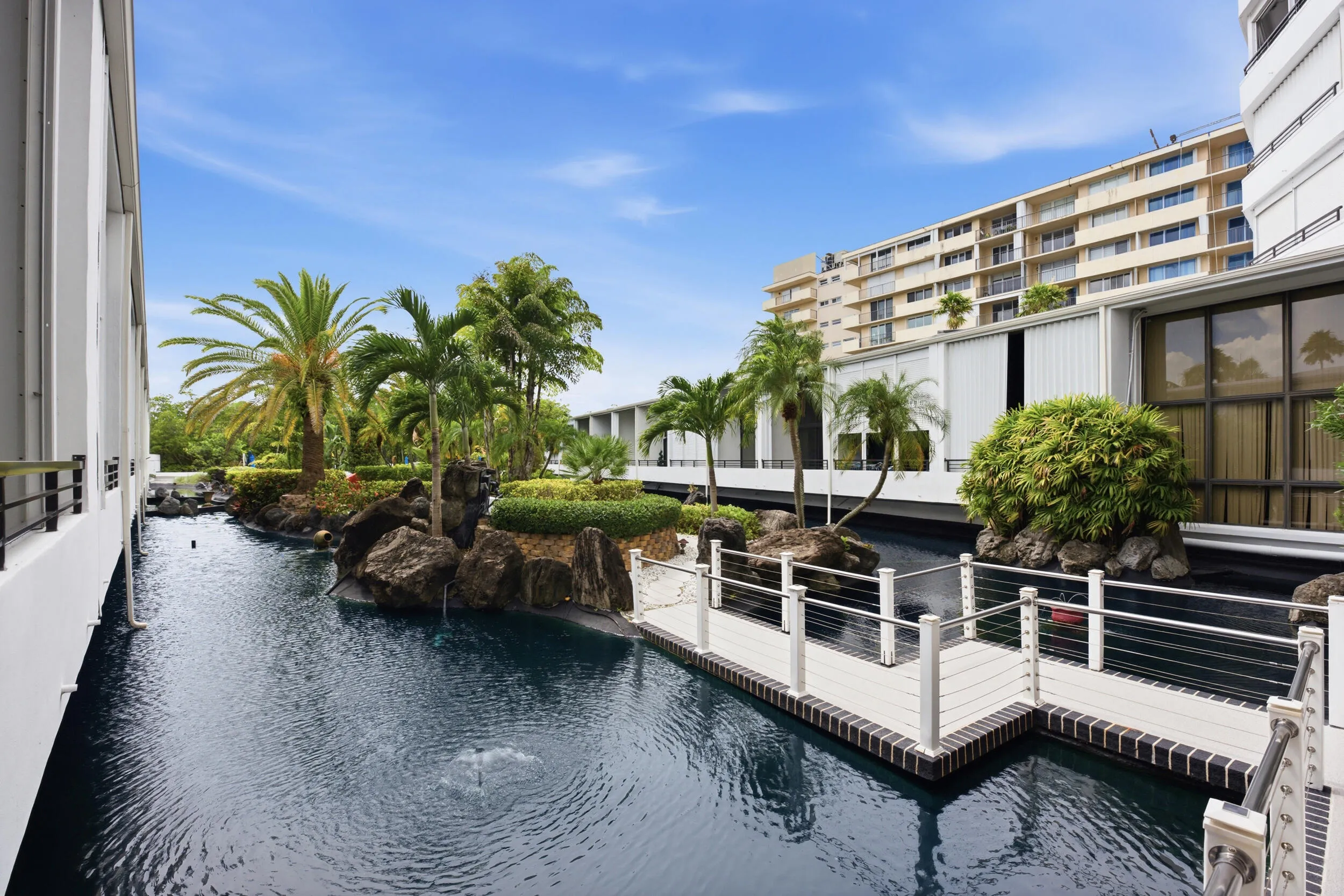 Tranquil water feature with a stone island and lush tropical plantings
