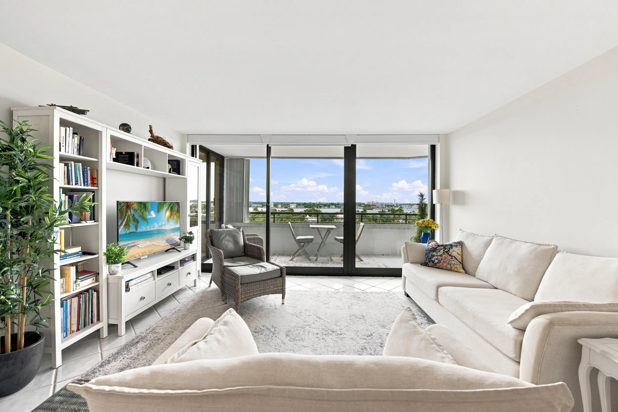 Living area featuring white walls, light-colored flooring, and direct access to a balcony through expansive glass sliders