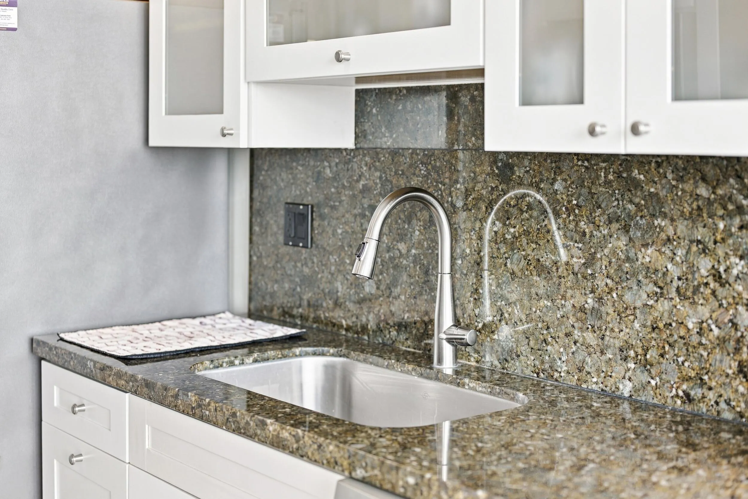 Kitchen sink area featuring a stainless steel undermount sink, gooseneck faucet, and coordinating countertop and backsplash