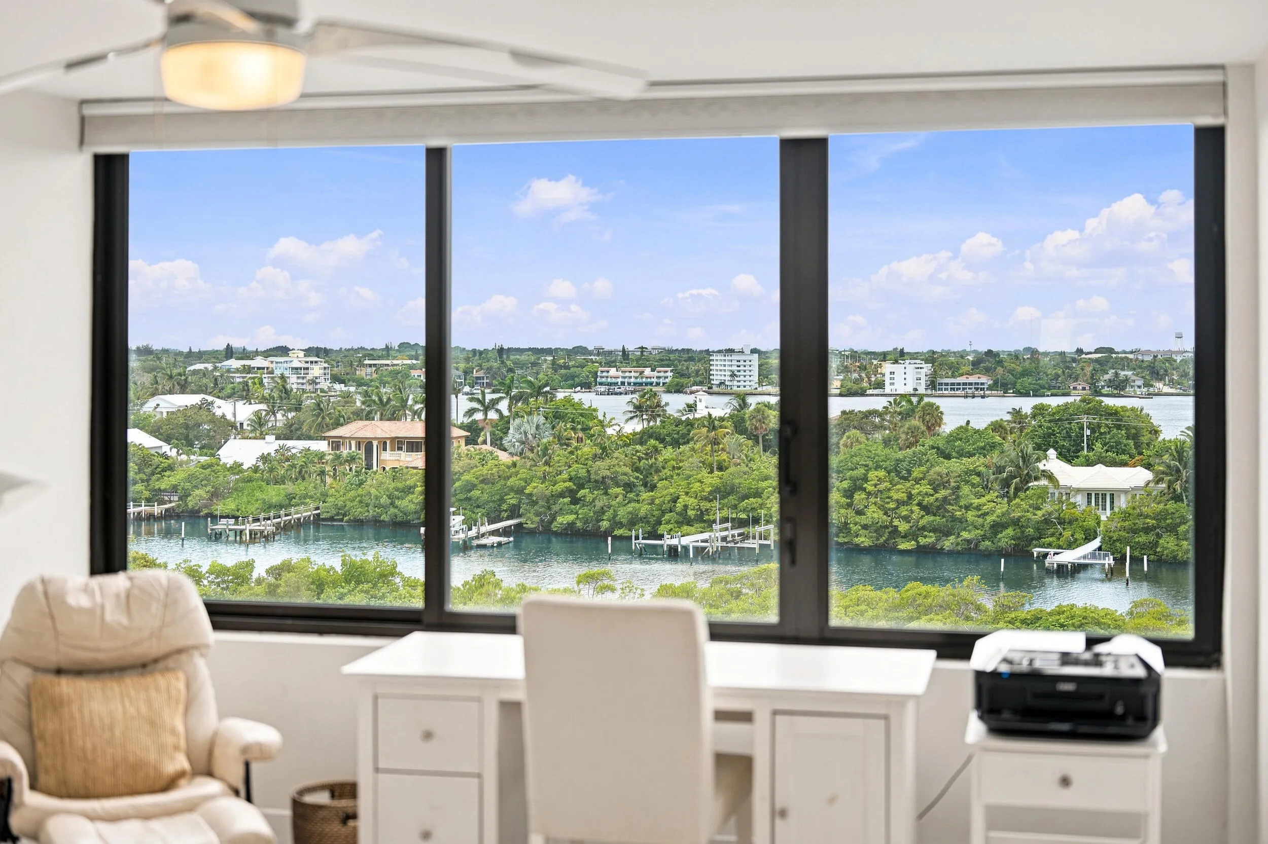 Expansive windows showcasing a waterfront landscape with residential architecture and lush greenery