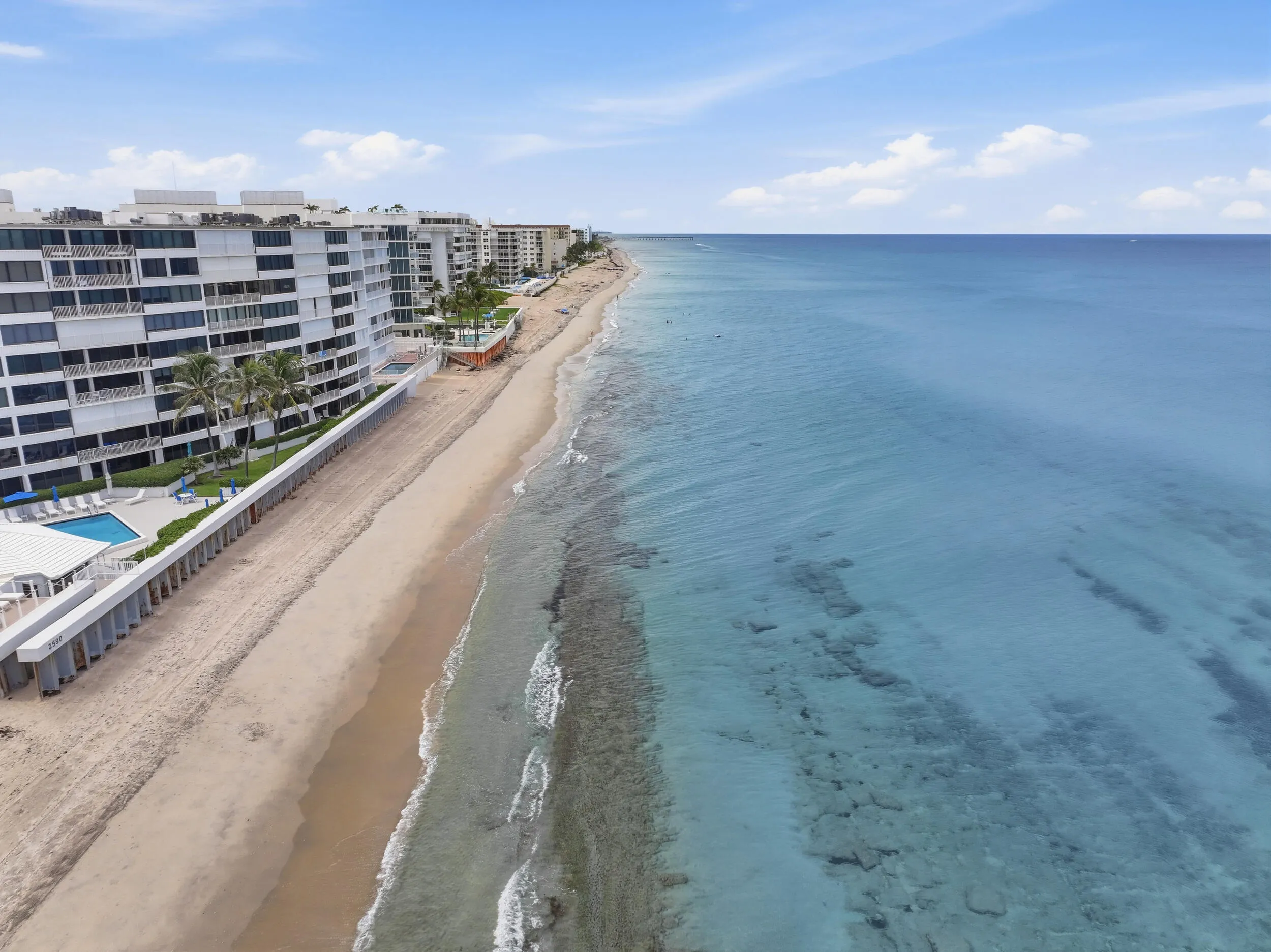 Waterfront condominiums featuring a private swimming pool, direct beach access, and clear blue ocean waters