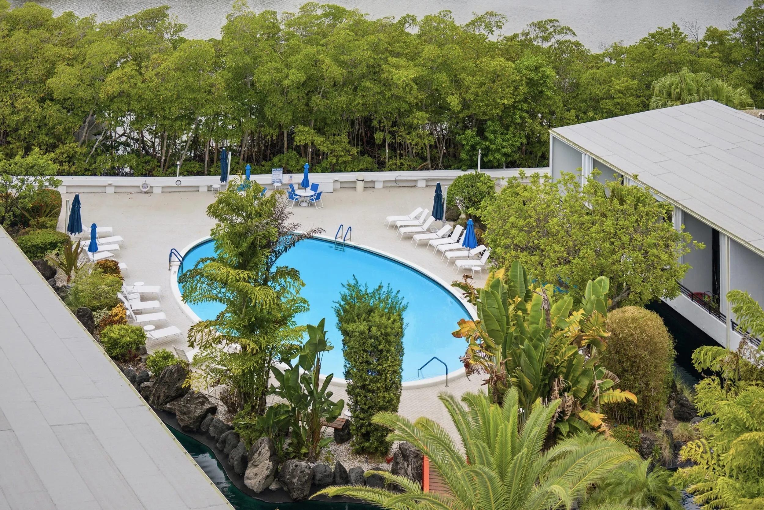 Curved swimming pool with ample lounge seating on a paved deck