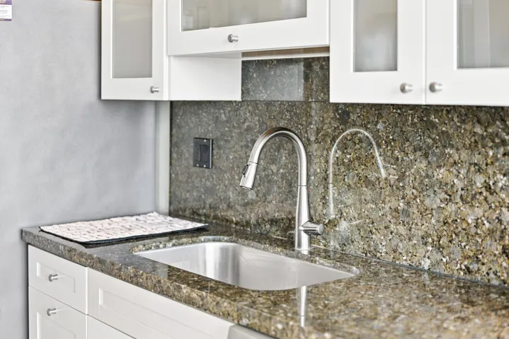 Kitchen sink area featuring a stainless steel undermount sink, gooseneck faucet, and coordinating countertop and backsplash