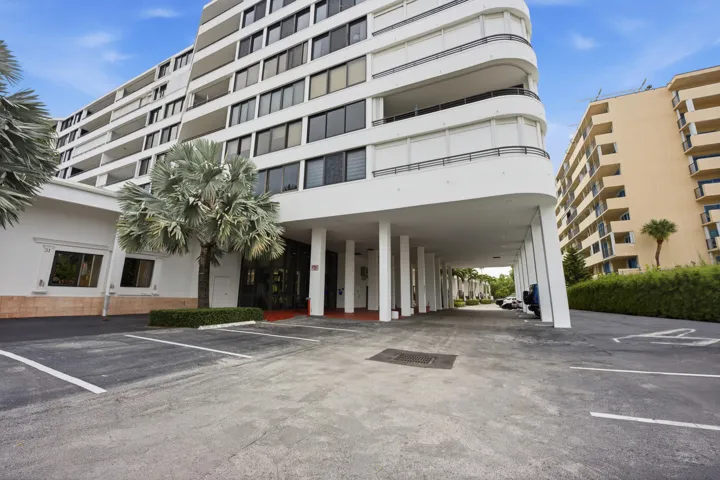 Multi-story building featuring white facade, dark-tinted windows, and multiple balconies
