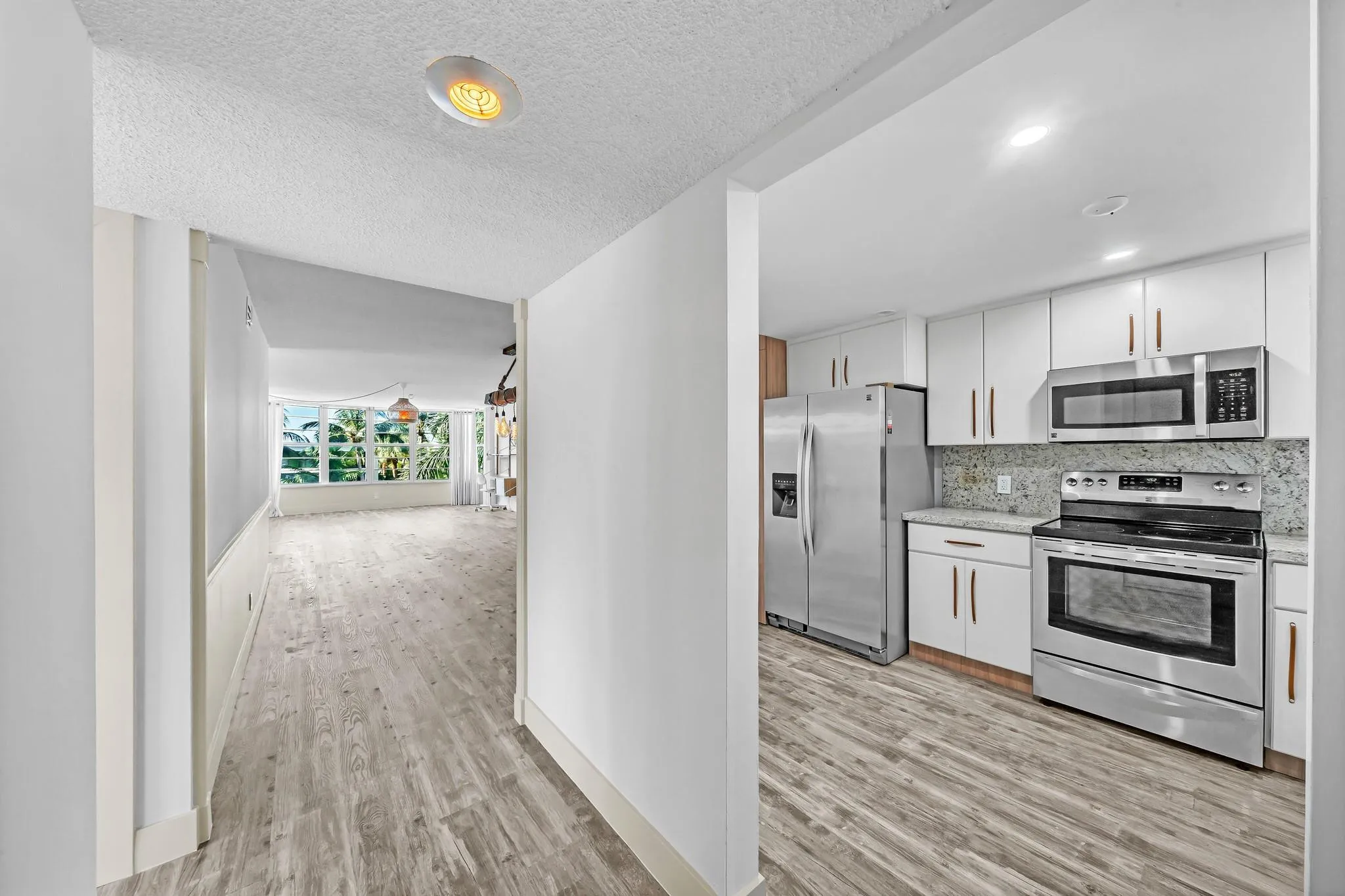 Modern kitchen featuring stainless steel appliances, white cabinetry, and a light-toned backsplash