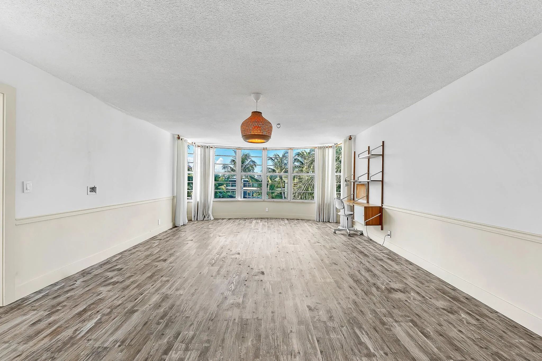 Wood-finish flooring, half-wall wainscoting, and a curved window wall with multiple windows
