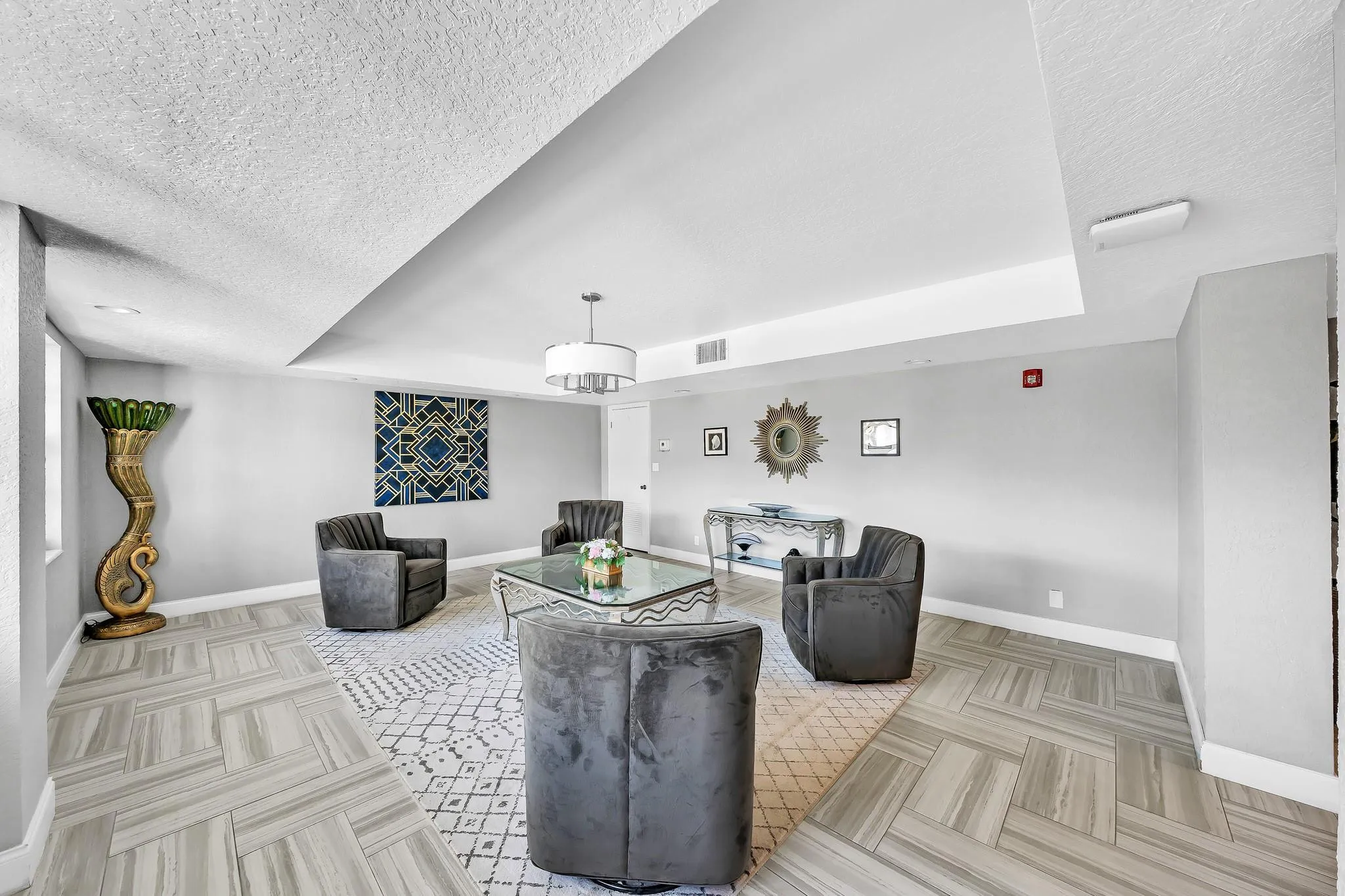 Recessed lighting, contemporary chandelier, textured ceiling, tiled flooring with a herringbone pattern, light gray wall color
