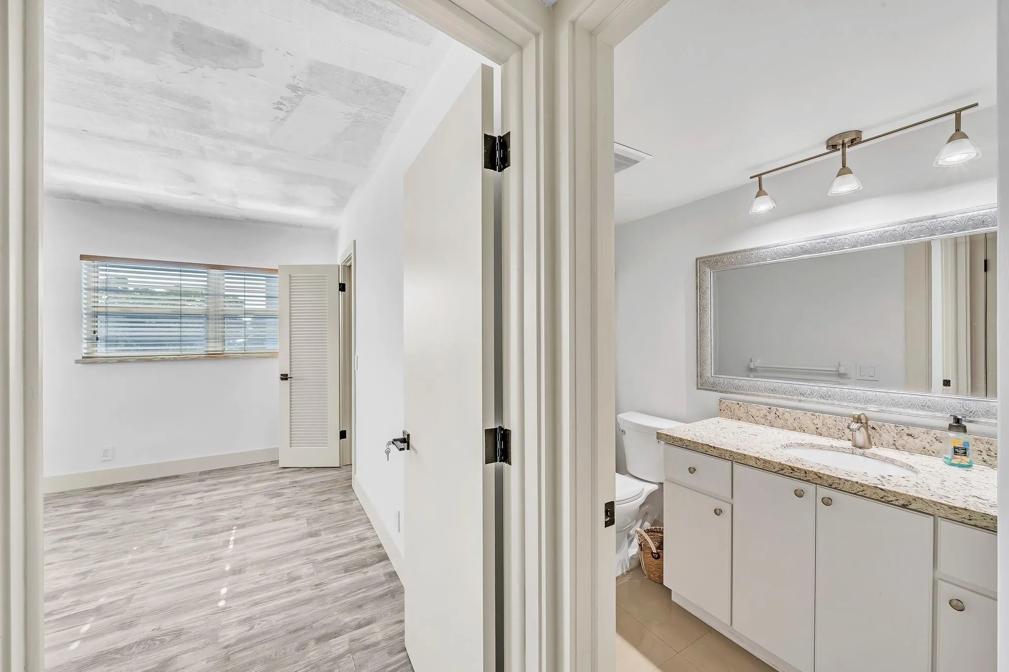 Bathroom vanity with a light-colored countertop, white cabinetry, and a large framed mirror