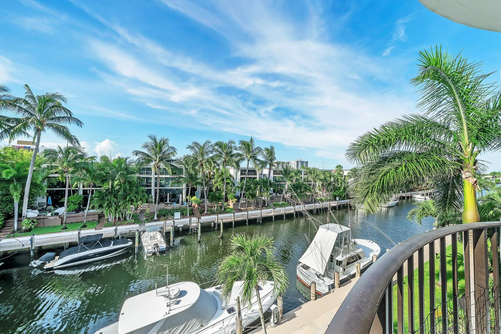 Waterfront property featuring a private dock, lush palm trees, and canal access