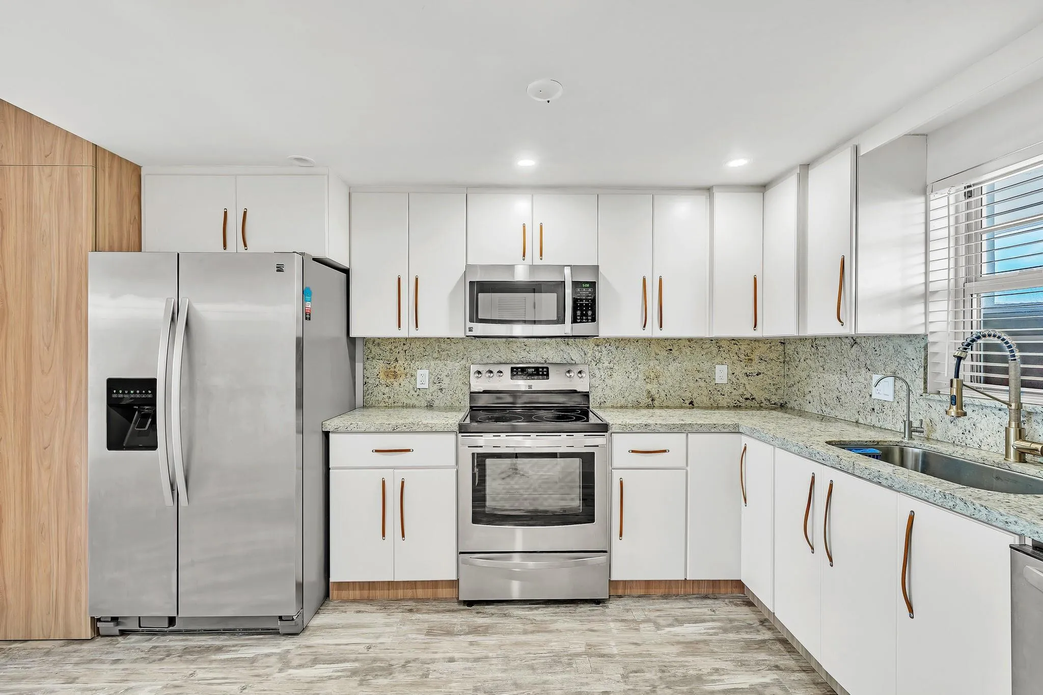 Kitchen featuring white cabinetry, stainless steel appliances, speckled countertops, and a full-height backsplash