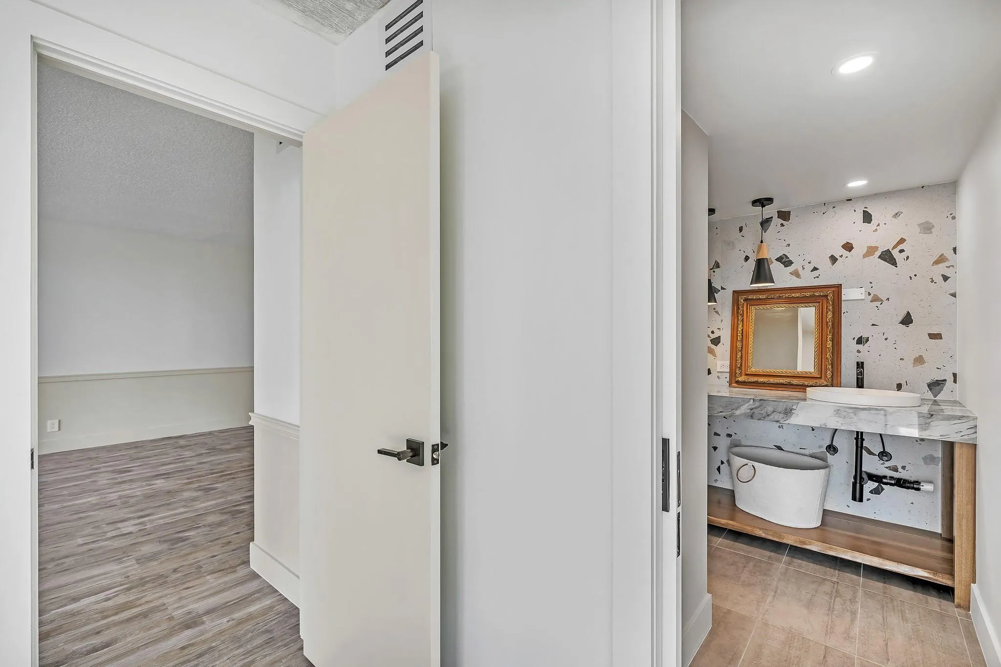 Hallway with wood-finish flooring and a white paneled door