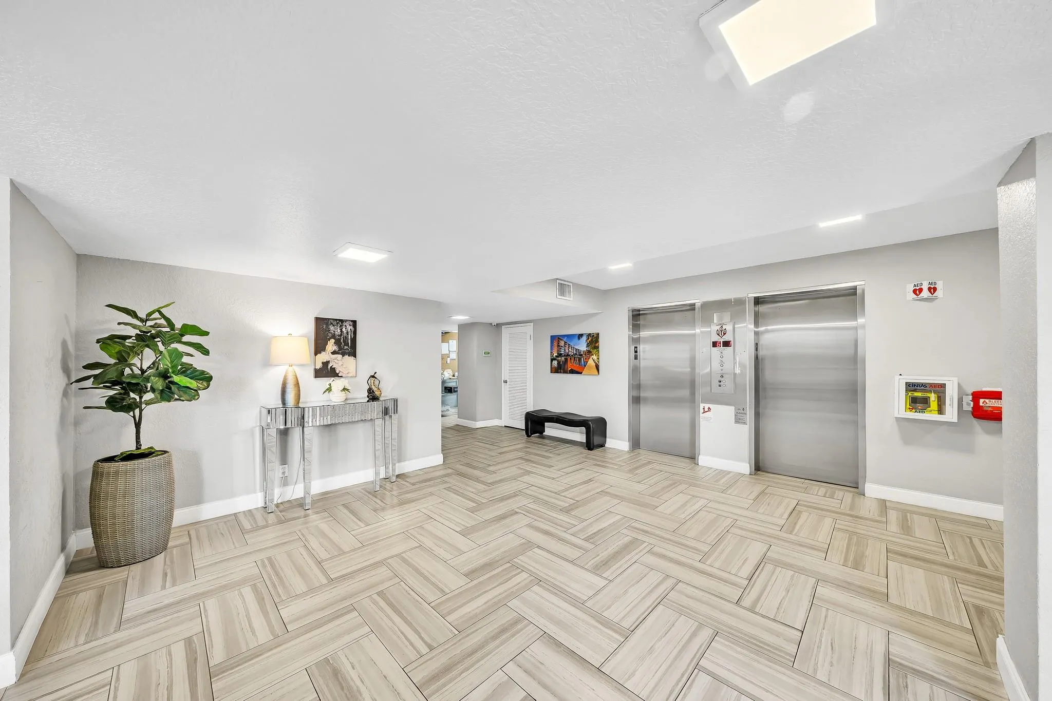 Herringbone-patterned wood-finish flooring, recessed lighting, and dual stainless steel elevators