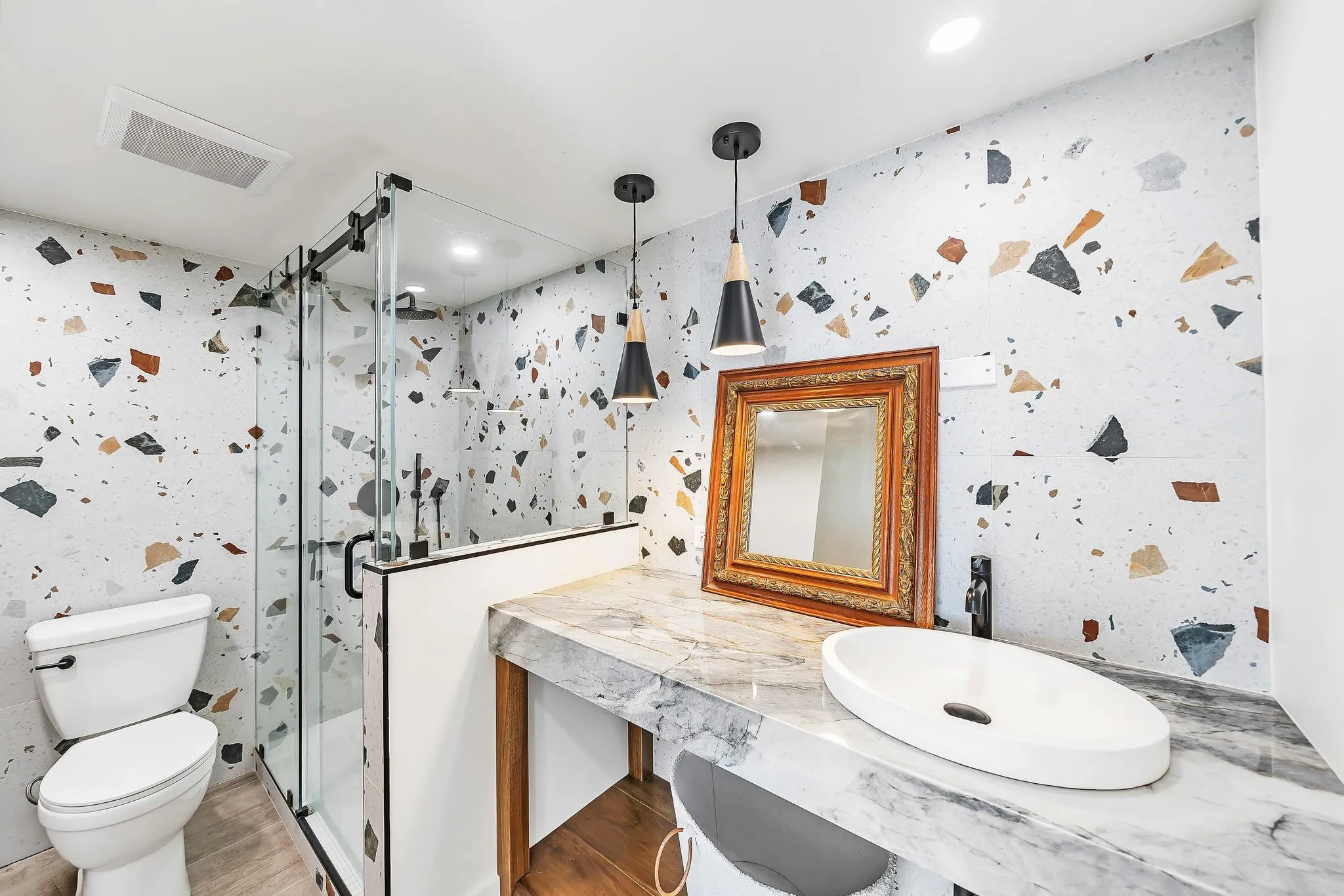 Glass-enclosed shower with matte black fixtures, a white vessel sink, and a marbled countertop