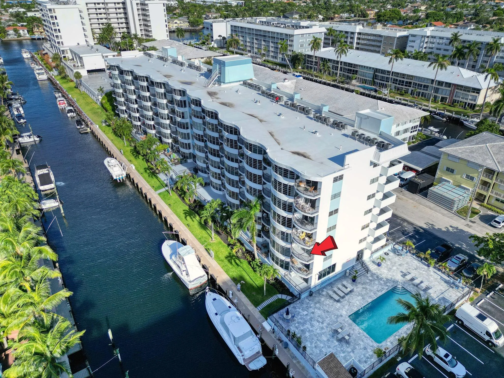 Waterfront property featuring a multi-story building with multiple balconies, a swimming pool, and dedicated parking