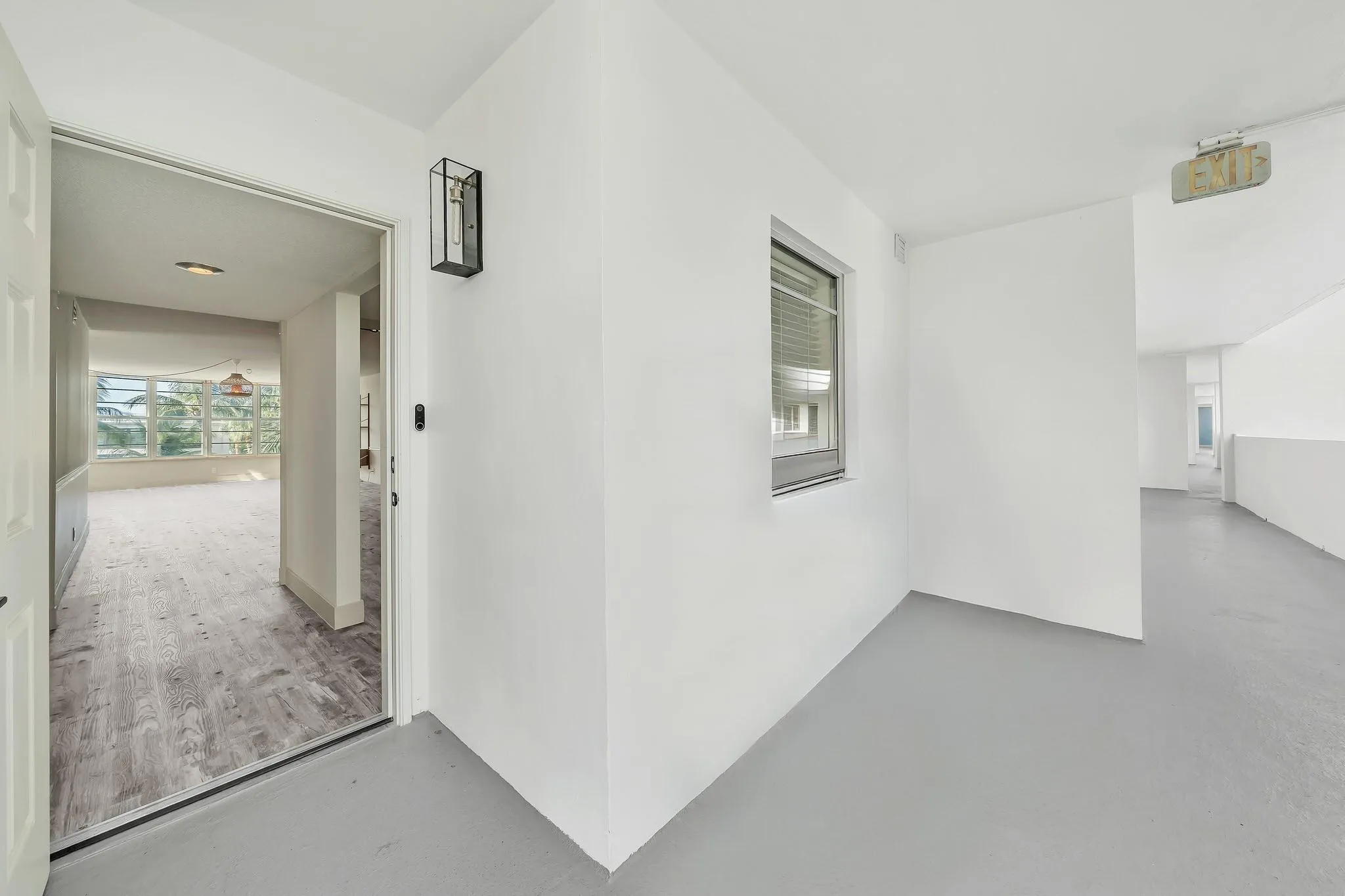 Wood-finish flooring, white painted walls, and a contemporary wall sconce
