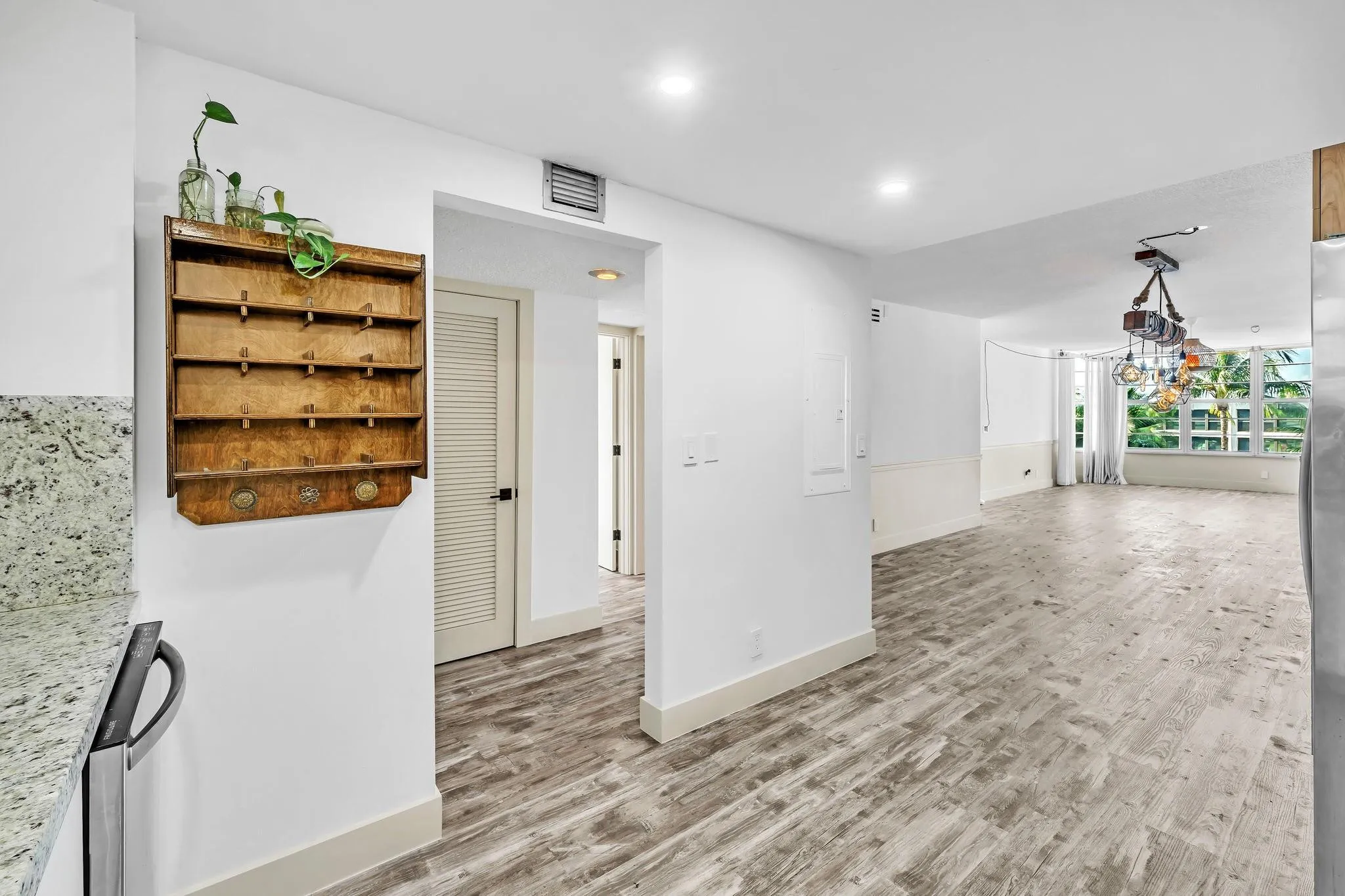 Wood-finish flooring throughout, white baseboards, recessed lighting, and a modern multi-light fixture