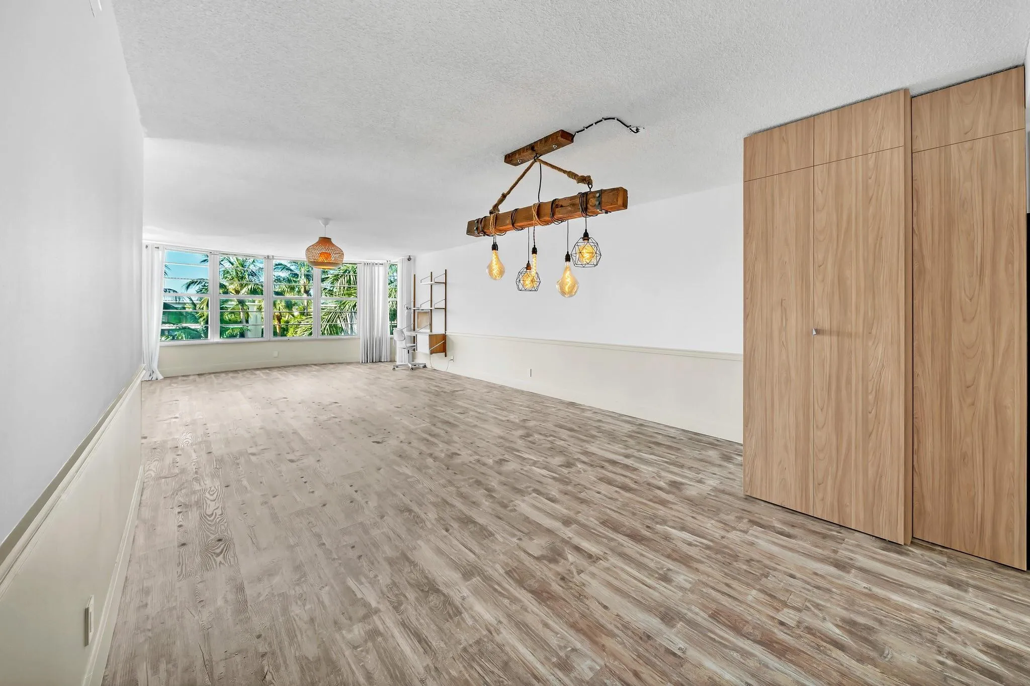Wood-finish flooring throughout, featuring a natural wood beam chandelier and a large picture window with outdoor scenery