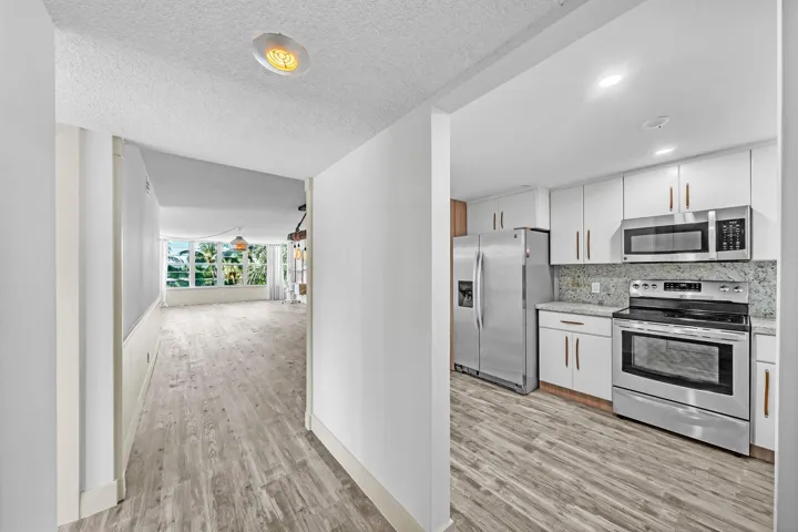 Modern kitchen featuring stainless steel appliances, white cabinetry, and a light-toned backsplash