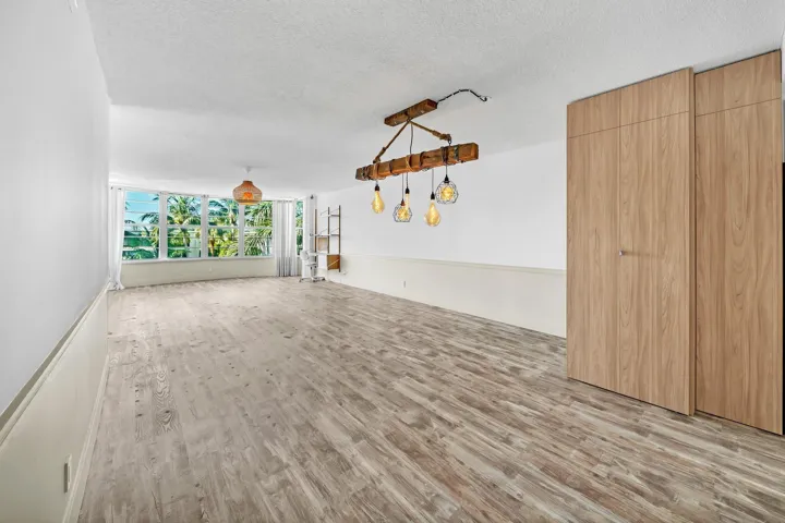 Wood-finish flooring throughout, featuring a natural wood beam chandelier and a large picture window with outdoor scenery