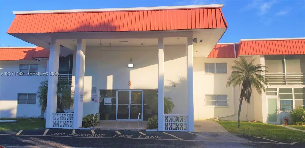 Welcoming covered building entrance with a clean, well-maintained exterior, tropical landscaping, and convenient access to the main lobby.