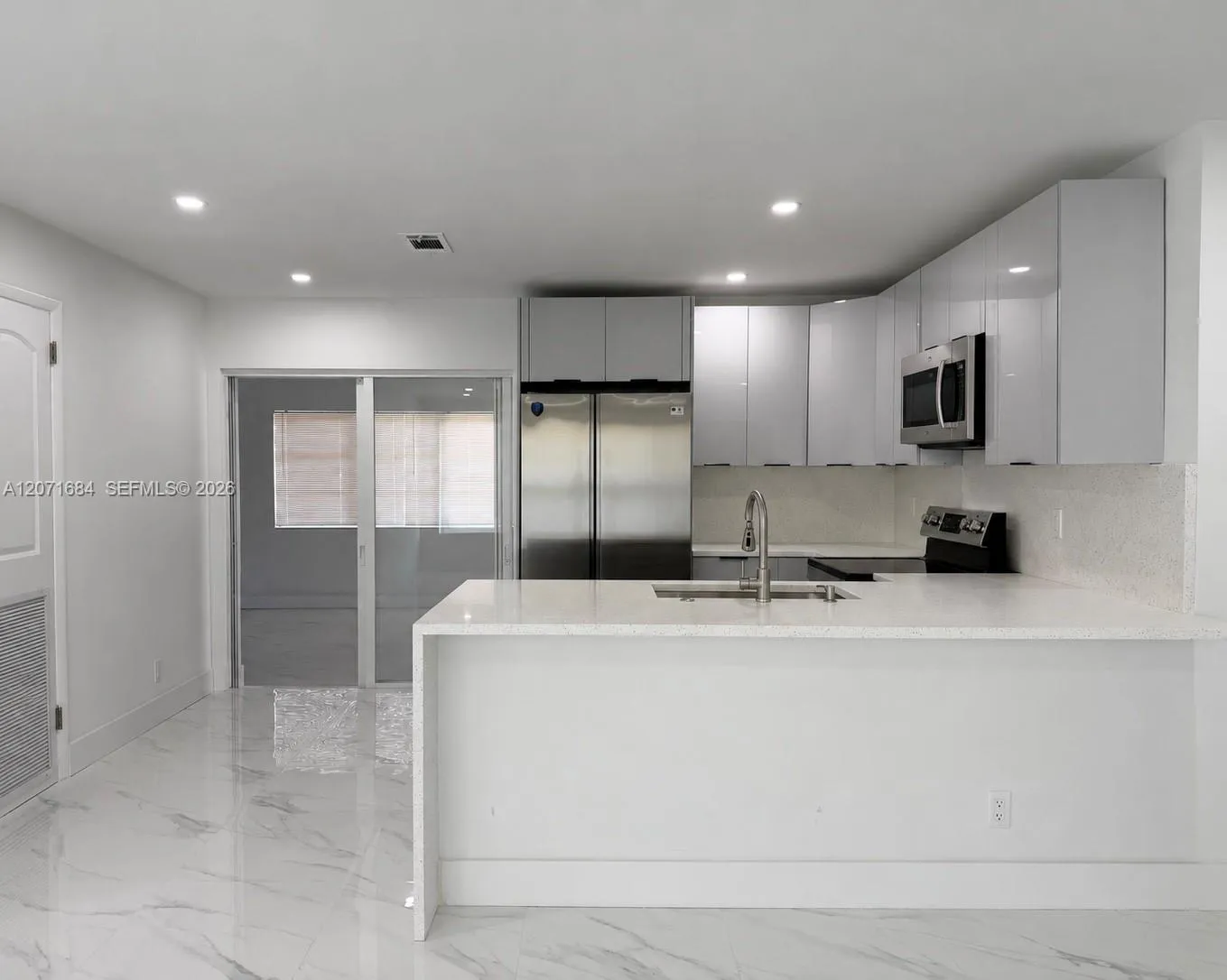 Renovated kitchen with stone countertops and stainless-steel appliances. Digitally modified microwave added for illustration