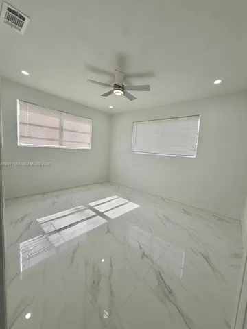Primary bedroom with tile flooring, ceiling fan and natural light