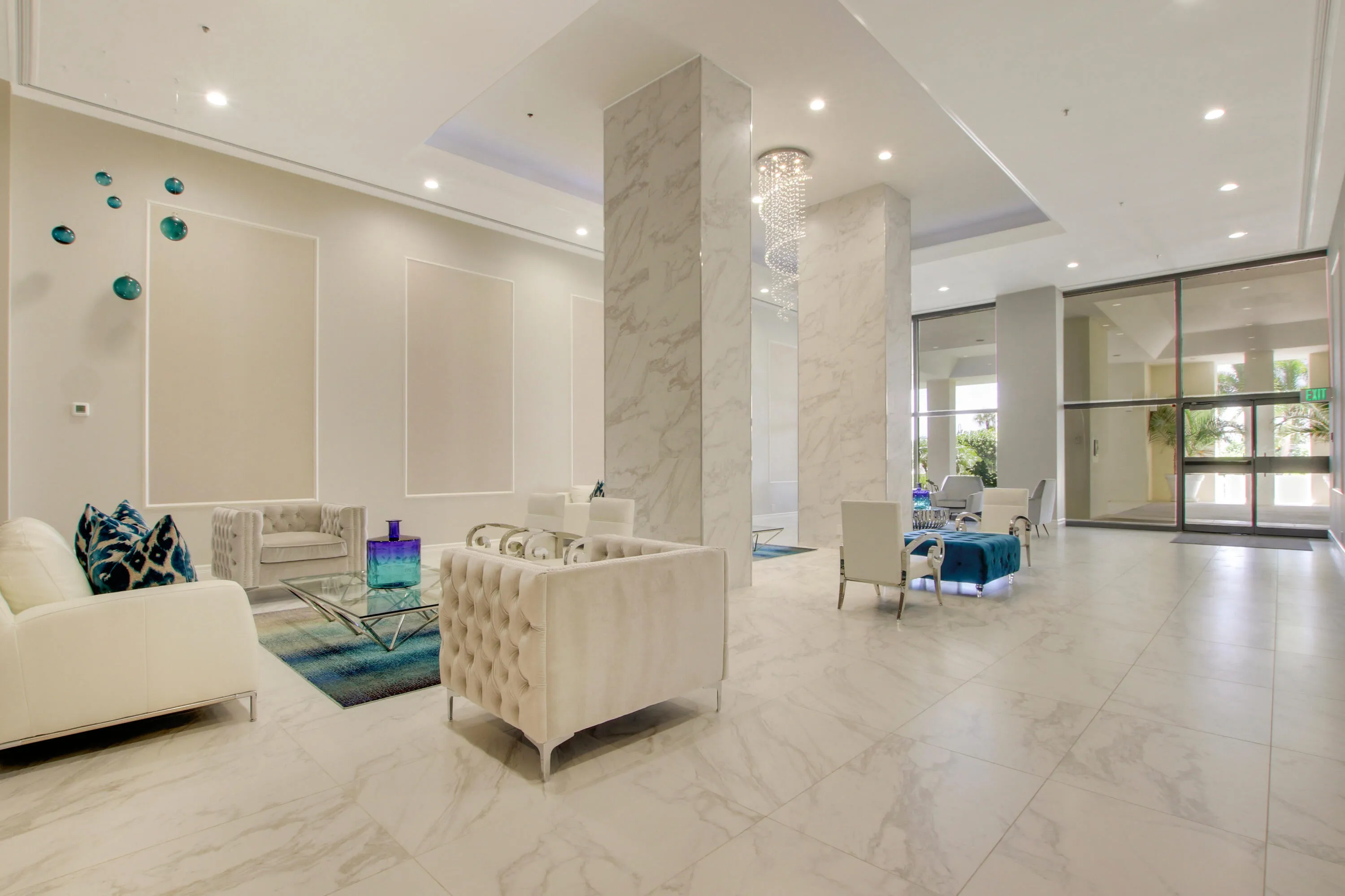 Polished tile flooring, marble-clad columns, recessed lighting, and a modern chandelier