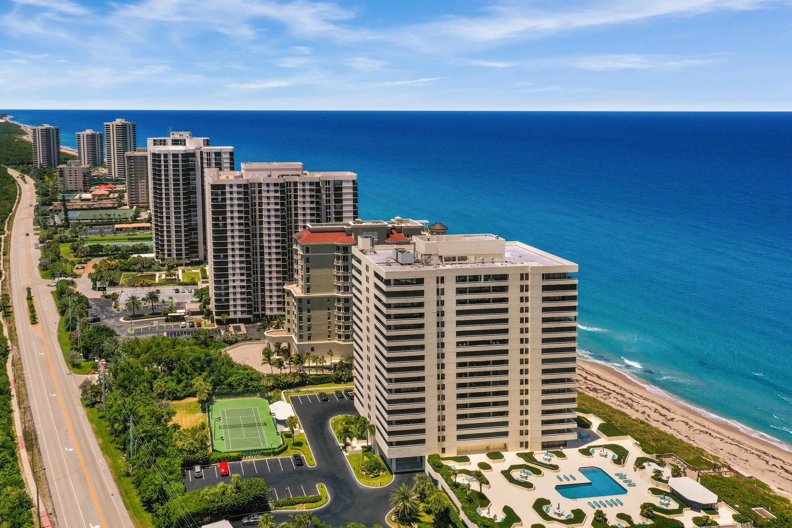 Coastal high-rise architecture with direct beach frontage, a swimming pool terrace, and tennis courts