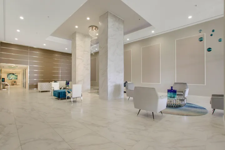 Spacious entryway featuring large format tile flooring, recessed lighting, decorative wall panels, and a tiered chandelier