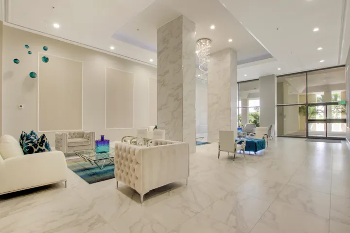 Polished tile flooring, marble-clad columns, recessed lighting, and a modern chandelier