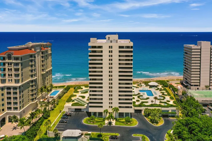 Waterfront high-rise building featuring multiple pools, structured landscaping, and a tennis court