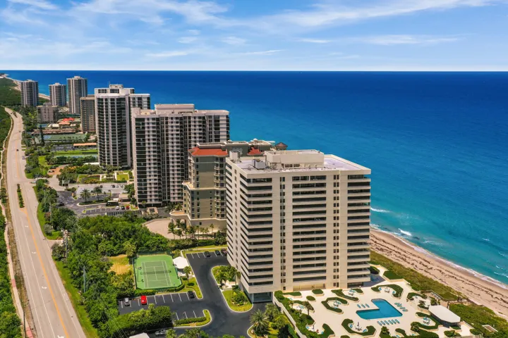 Coastal high-rise architecture with direct beach frontage, a swimming pool terrace, and tennis courts