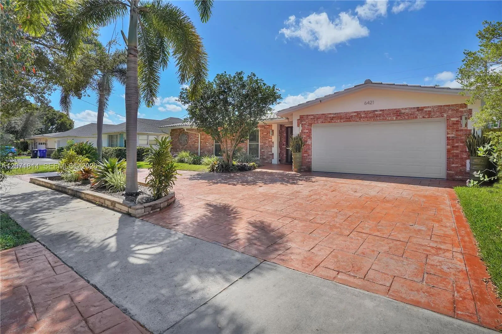 Beautifully landscaped curb appeal with paver driveway and lush greenery