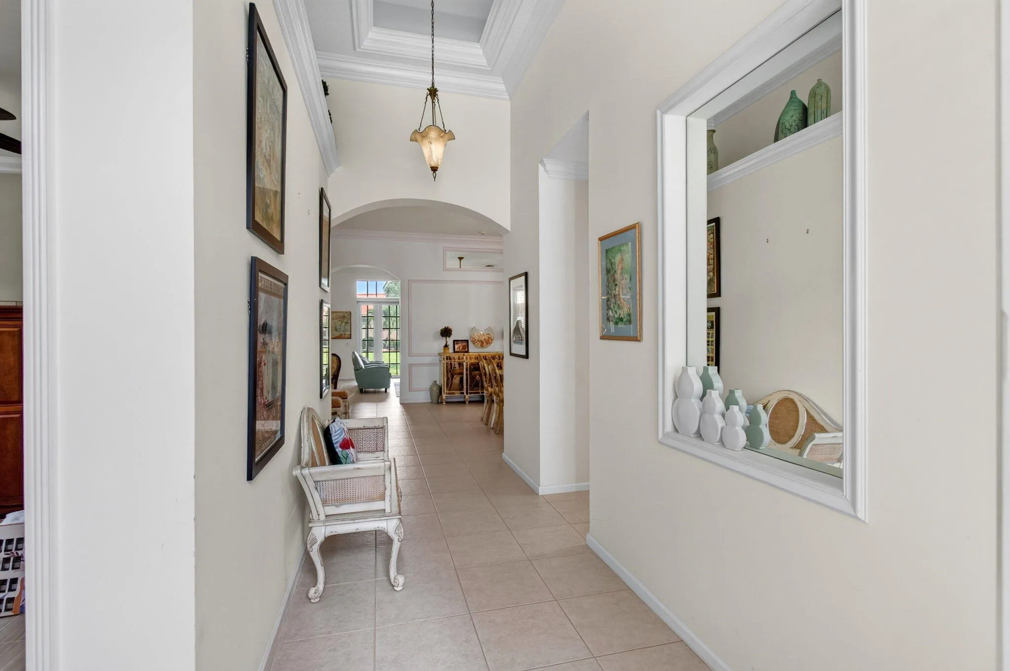 Tiled flooring throughout, tray ceiling with crown molding, archway entry, and an interior display niche