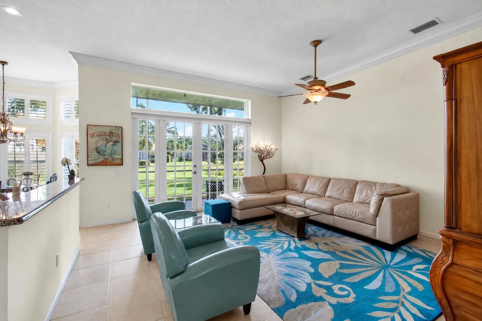Living space with light-toned tiled flooring, crown molding, and a ceiling fan