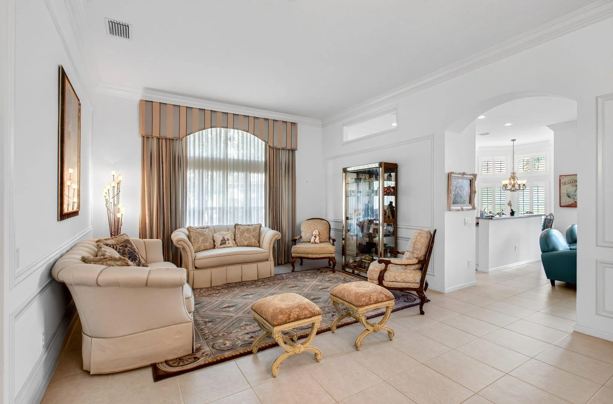 Arched window with custom valance, crown molding, chair rail molding, tile flooring, and an arched doorway