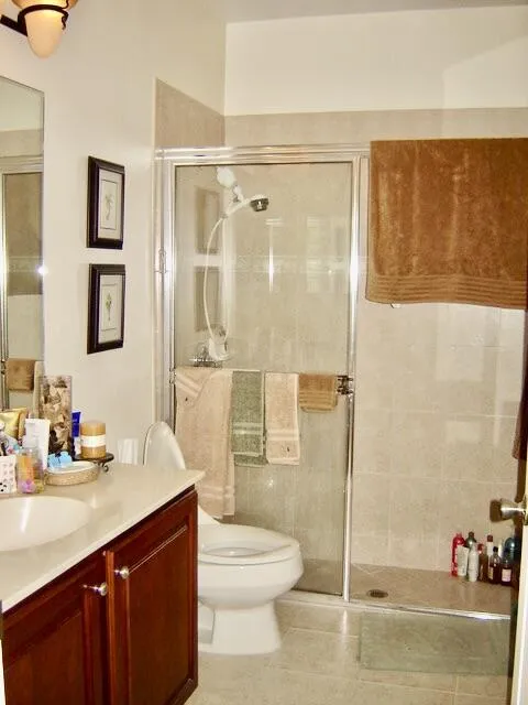 Built-in wood-finish vanity with an integrated sink, a glass-enclosed shower, and full-height wall tiling