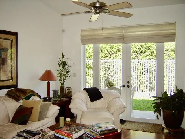 Vaulted ceiling with a ceiling fan, French doors with exterior fencing, and wood-finish flooring
