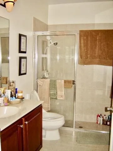 Built-in wood-finish vanity with an integrated sink, a glass-enclosed shower, and full-height wall tiling