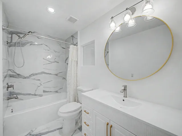 Modern bathroom featuring a white vanity with brass hardware, white quartz countertop, and rectangular vessel sink