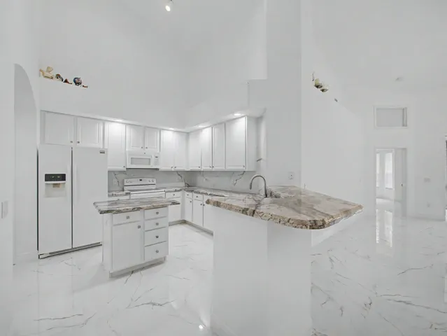 Kitchen featuring white cabinetry, light-toned countertops, a center island with storage, and stainless steel appliances